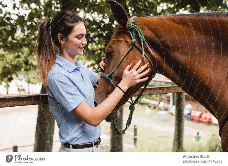 Weiblicher Jockey legt Pferd Zaumzeug an Frau Pferdestall vorbereiten angezogen Reiterin Tier beschäftigt Werkzeug Gerät Zügel pferdeähnlich jung Konzentration