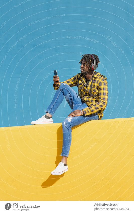 schwarzer Mann mit Kopfhörern, der sein Telefon konsultiert Person Musik Technik & Technologie Afrikanisch hören vertikal Mobile jung männlich Amerikaner Handy