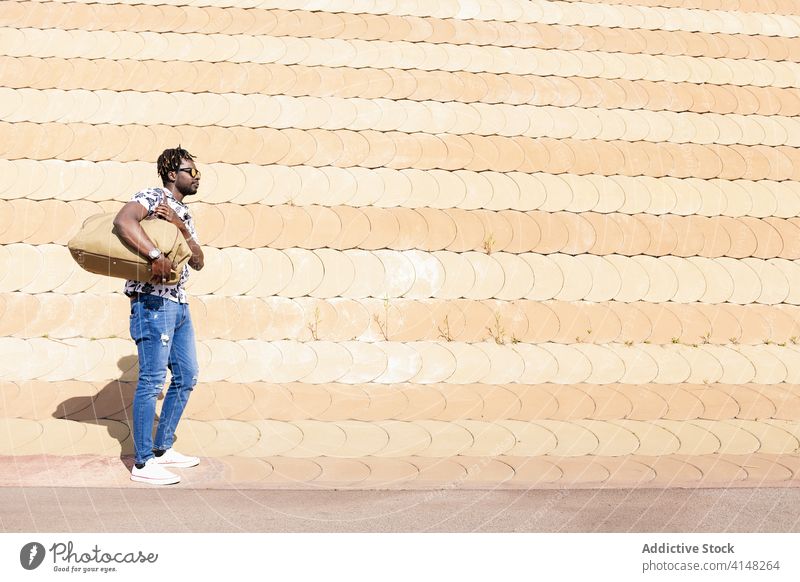 junger schwarzer Mann mit Sonnenbrille und Reisetasche Person Tasche groß männlich führen tragen Stehen Reisender Tourist gutaussehend Typ horizontal