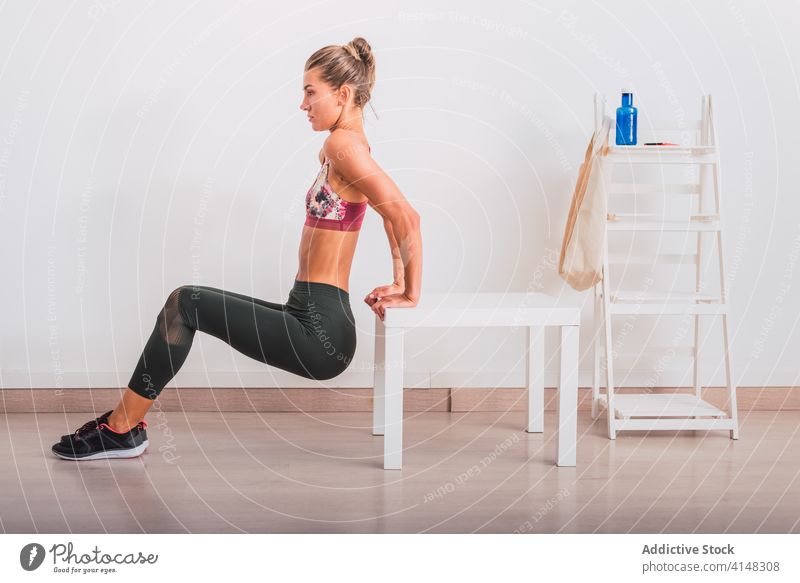 Schlanke Sportlerin, die auf einen kleinen Tisch in einer Wohnung gelehnt trainiert Aufwärmen Übung Training Energie Gleichgewicht Vitalität Bestimmen Sie