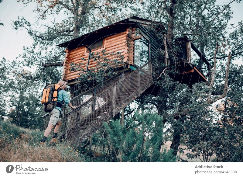 Reisender Mann in der Nähe eines Baumhauses im Wald Haus Kabine Hütte Rucksack Wälder hölzern Gebäude Abenteuer männlich reisen stehen Tourismus Natur Feiertag