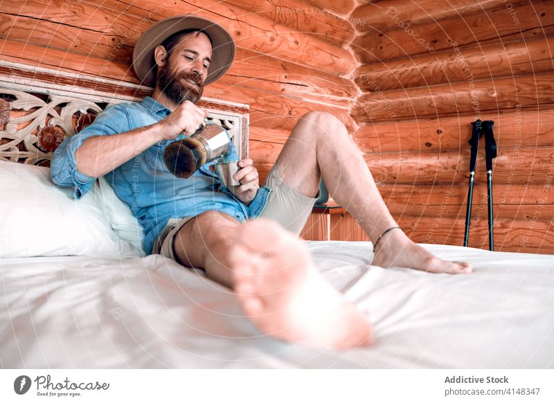 Entspannter Mann auf dem Bett mit Kaffee eingießen Morgen genießen hölzern Haus Schlafzimmer frisch Lächeln männlich heiß gemütlich sich[Akk] entspannen ruhen
