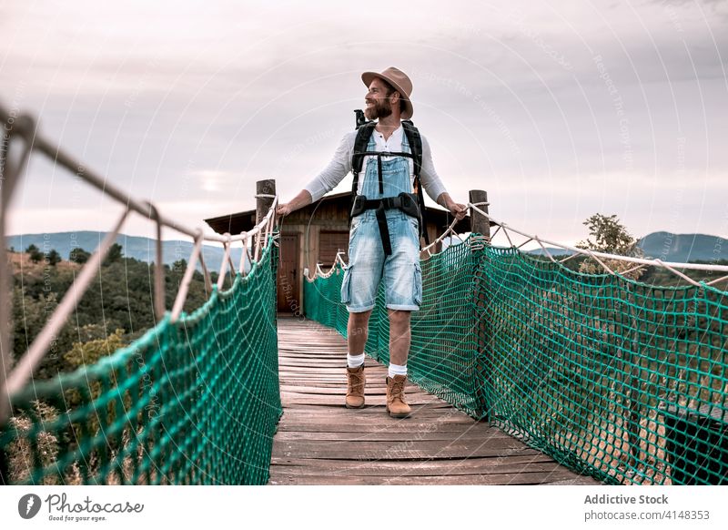 Reisender Mann zu Fuß entlang Holzsteg Suspension Steg Tourist Spaziergang Rucksack bewundern Landschaft hölzern Urlaub männlich Abenteuer Ausflug Tourismus