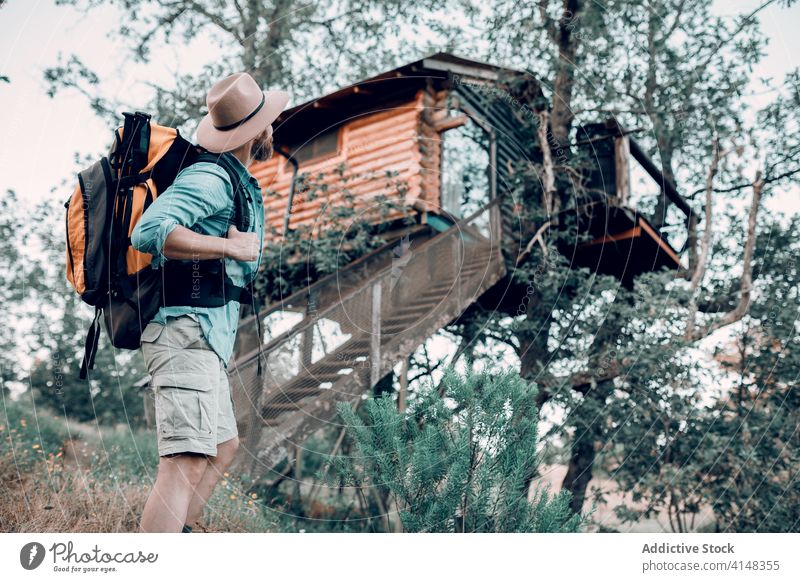 Reisender Mann in der Nähe eines Baumhauses im Wald Haus Rucksack Wälder hölzern Gebäude Abenteuer männlich reisen stehen Tourismus Natur Feiertag Landschaft