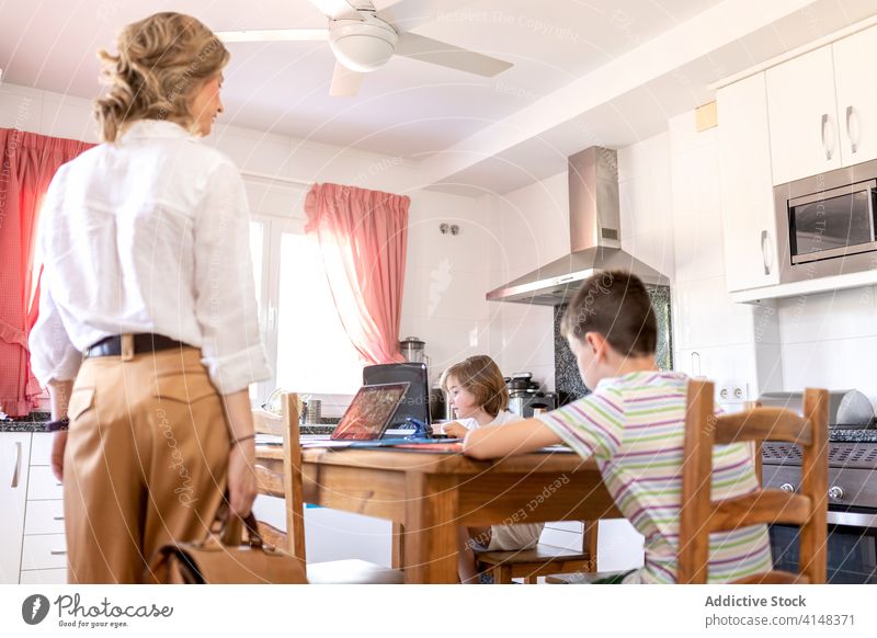 Kinder machen Hausaufgaben mit Laptop in der Nähe von stilvollen Mutter in der Küche Bildung Wissen lernen benutzend Apparatur Gerät Tablette Netbook stylisch