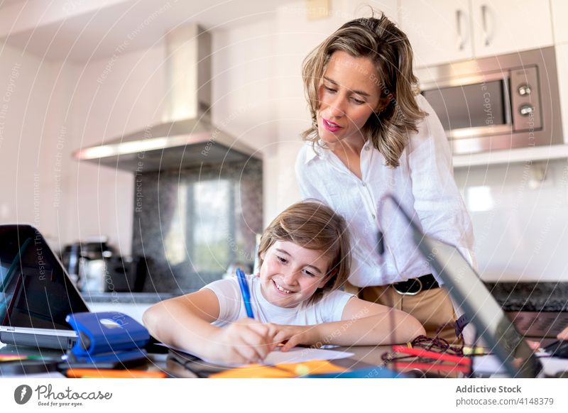 Geschäftsfrau überprüft Hausaufgaben, während sie in der Nähe des positiven Sohnes zu Hause steht Mutter prüfen Junge lernen Bildung Aufgabe heimisch Kindheit