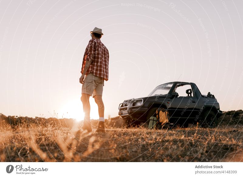 Unbekannter männlicher Reisender bewundert die Landschaft in der Nähe des Autos im Sonnenlicht Tourist bewundern Natur PKW Gras Ausflug Urlaub Harmonie