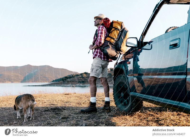 Tourist mit Rucksack stehen in der Nähe von Hund und Auto bewundern Natur nachdenken Hochland reisen Automobil Fluss Berge u. Gebirge idyllisch Harmonie