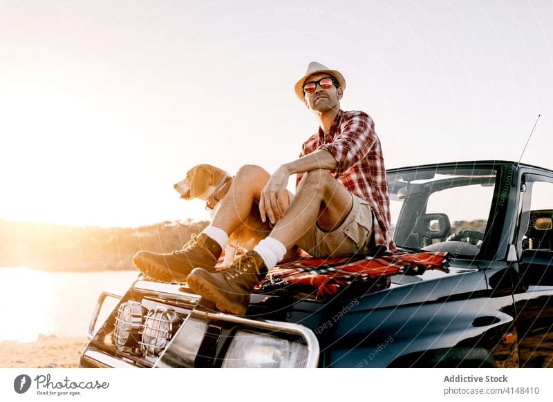 Tourist mit Hovawart genießt die Natur auf dem Auto sitzend im Sonnenlicht Hund bewundern Fluss Berge u. Gebirge PKW Urlaub Schönheit idyllisch nachdenken