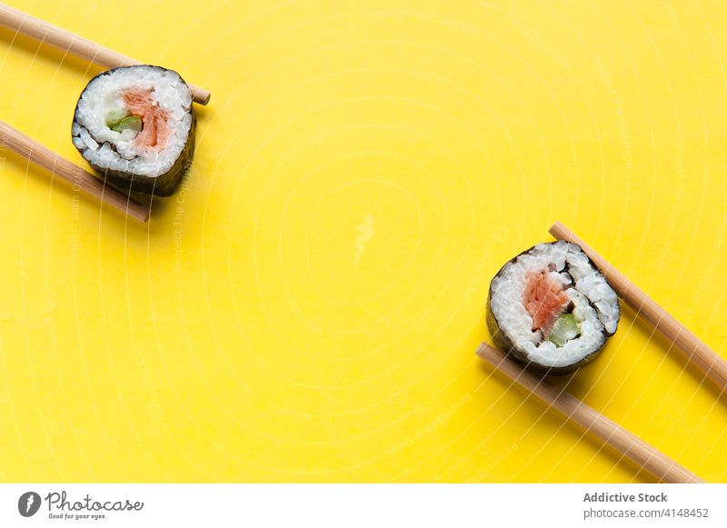 Appetitliche Brötchen und Stäbchen auf gelbem Hintergrund rollen Sushi Essstäbchen Atelier Lachs Reis lecker Asiatische Küche geschmackvoll Tradition