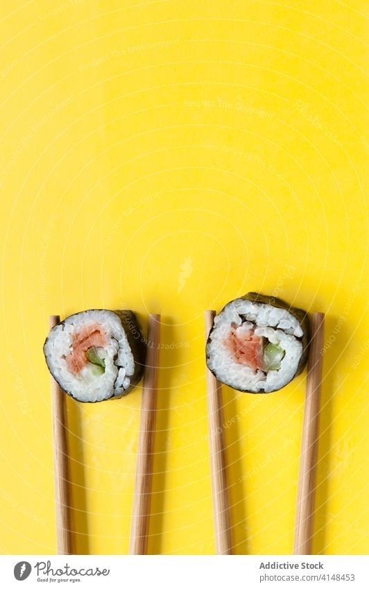 Appetitliche Brötchen und Stäbchen auf gelbem Hintergrund rollen Sushi Essstäbchen Atelier Lachs Reis lecker Asiatische Küche geschmackvoll Tradition