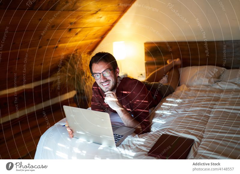 Konzentrierter männlicher Freiberufler, der zu Hause am Laptop tippt Tippen freiberuflich abgelegen Mann Arbeit Projekt Unternehmer benutzend heimwärts Bett