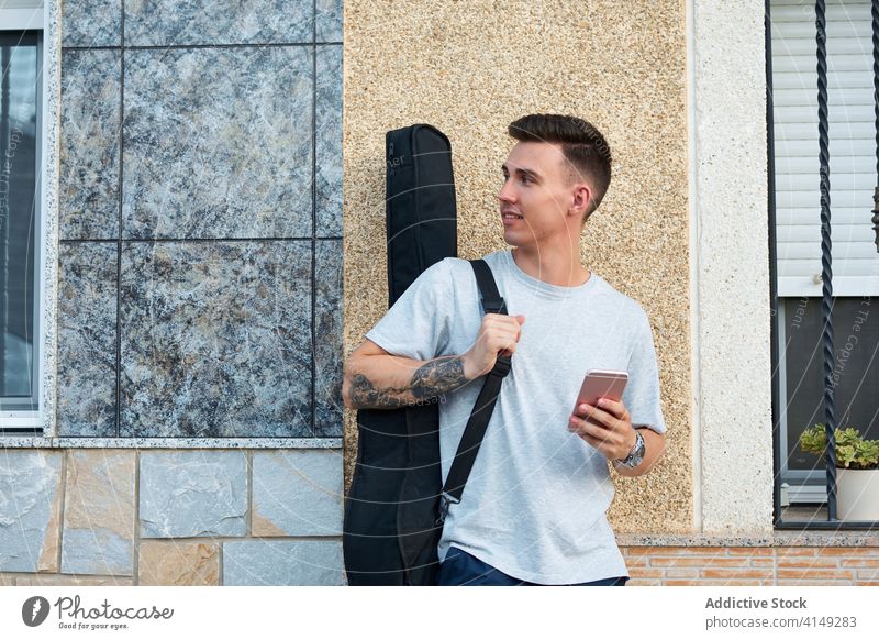 Mann mit Gitarre und Smartphone in der Stadt lesen Nachricht soziale Netzwerke Großstadt benutzend Gitarrenspieler Musiker männlich Inhalt Gerät Apparatur