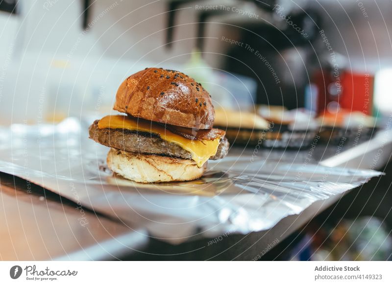 Frischer Hamburger mit Patty und Käse Burger Fastfood Kotelett Pastetchen Mahlzeit Rindfleisch Brötchen Folie Tradition dienen Küche appetitlich frisch