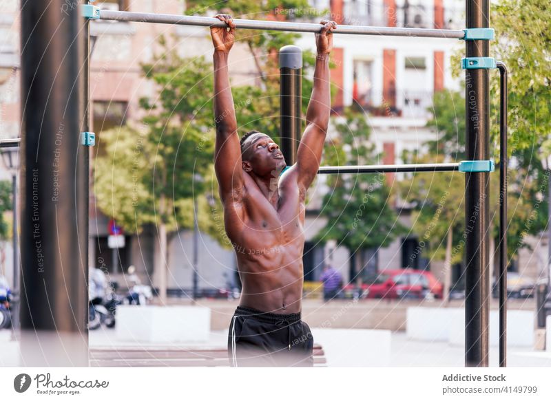 Muskulöser schwarzer Sportler macht Klimmzüge hochziehen Training stark Übung Athlet anstrengen Ausdauer nackter Torso männlich ethnisch Afroamerikaner intensiv
