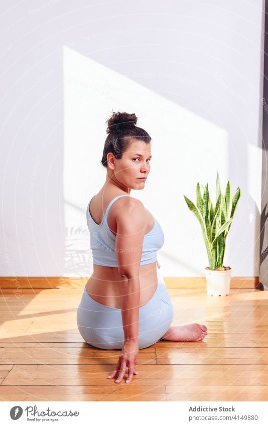 Ruhige Frau macht Yoga in Cow Face Position Kuhgesichtshaltung Pose beweglich üben Barfuß heimwärts positionieren gomukhasana Gesundheit Wellness mental
