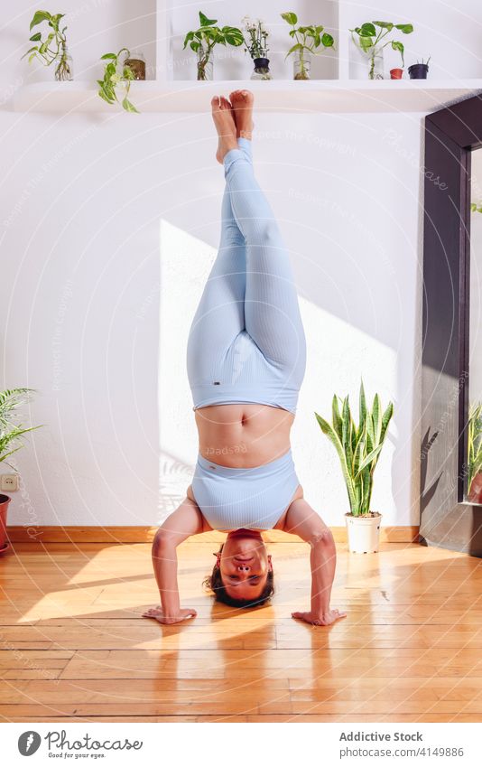 Frau macht Yoga in unterstützter Kopfstand-Pose unterstützte Kopfstand-Pose Salamba sirsasana beweglich Gleichgewicht heimwärts mollig Gesundheit hölzern Stock