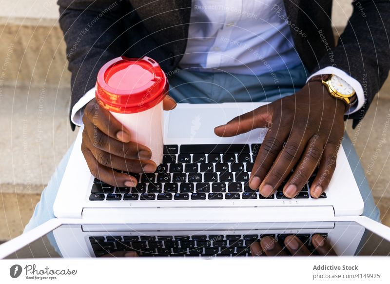 Anonymer schwarzer Mann, Unternehmer mit Laptop und Kaffee auf der Straße Geschäftsmann trinken benutzend urban selbstbewusst formal modern jung Afroamerikaner