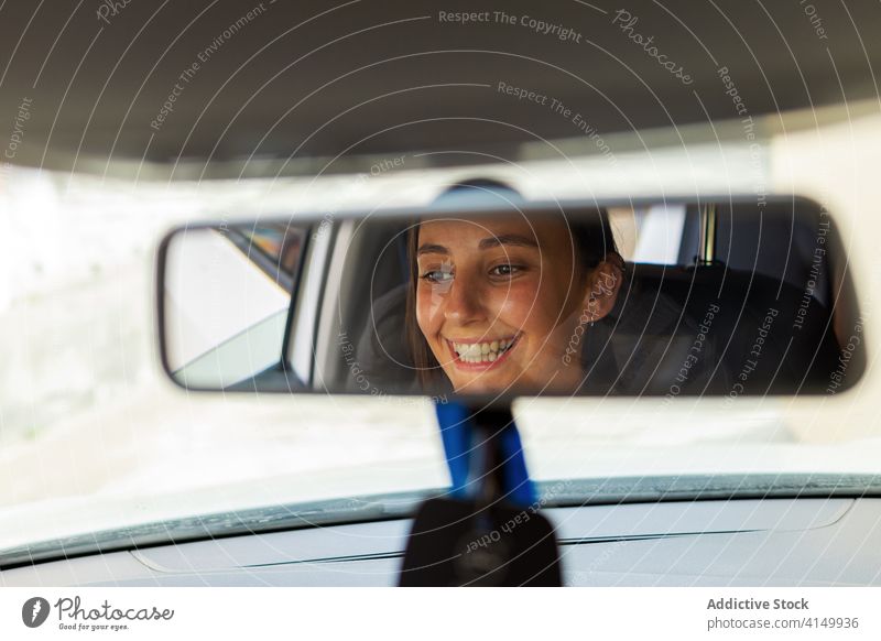 Lächelnde Frau im Auto sitzend Fahrer Spiegel PKW Rückansicht Verkehr Fahrzeug Automobil heiter modern Laufwerk Ausflug Reflexion & Spiegelung Fenster positiv