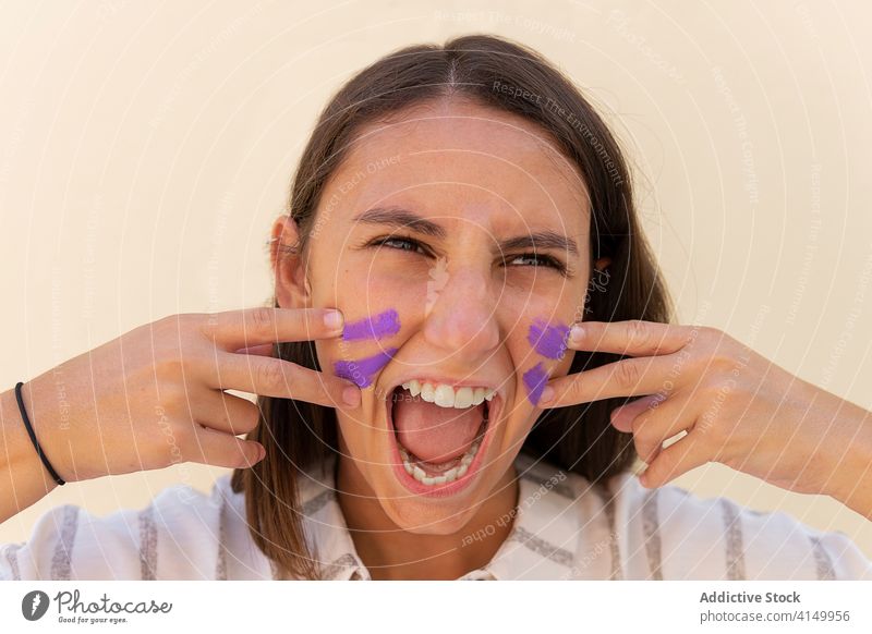 Aggressive Frau malt Gesicht in der Stadt Frauenpower Konzept Kraft Krieg Farbe Feminismus stark manifestieren schreien gestikulieren selbstbewusst weinen