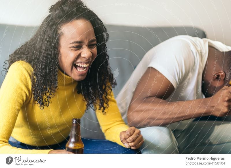 schwarzes Paar lachend und Bier trinken zu Hause Afrikanisch Party Glück Amerikaner heimwärts Alkohol Spaß Freunde Lächeln Zusammensein Freundschaft Person Frau