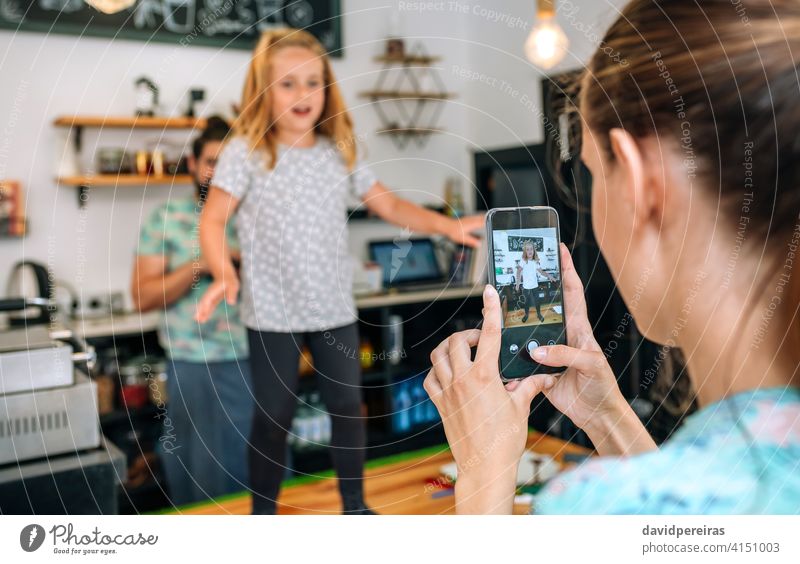 Mutter nimmt ihre Tochter beim Tanzen mit dem Handy auf, während sie in einem Café arbeitet Aufnahme Video soziale Netzwerke Glück Familie Arbeit Bild Foto