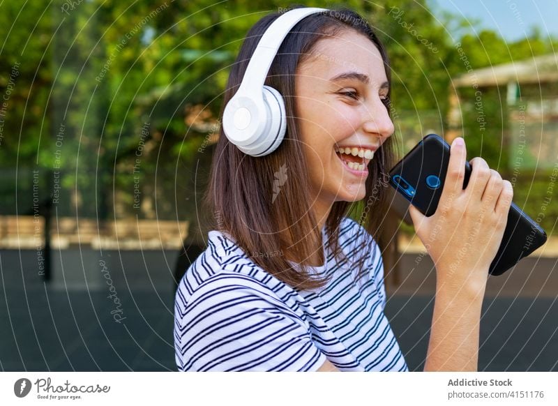Lächelnde Frau genießt Lieder mit Kopfhörern zuhören Musik Smartphone genießen heiter Drahtlos Großstadt benutzend Gebäude jung Klang modern Freude Gesang Glück