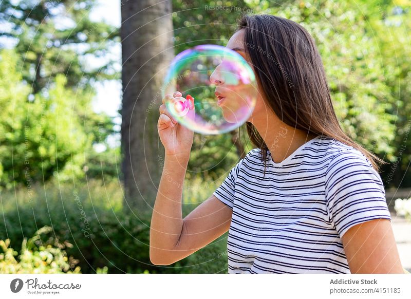 Junge Frau bläst Seifenblasen im Park Schlag Schaumblase kindisch sorgenfrei Sommer unterhalten genießen spielerisch Garten grün sich[Akk] entspannen Wochenende