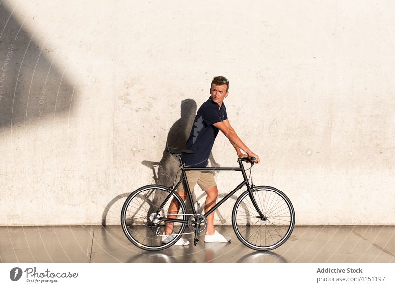 Mann mit Fahrrad an Betonwand Erwachsener blond lässig Kaukasier Textfreiraum Fahrradfahren Radfahrer Lifestyle männlich tausendjährig Mobilität modern Menschen