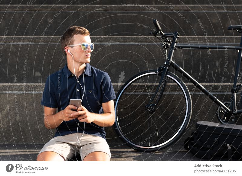 Mann sitzt auf der Treppe auf dem Smartphone Fahrrad blond Business Kaukasier Handy Mitteilung Textfreiraum Fahrradfahren Radfahrer Unternehmer freiberuflich