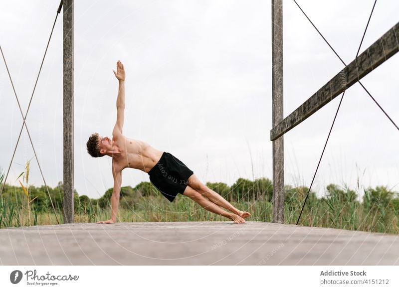 Flexibler Mann beim Yoga in der Side Plank Pose Seitenbrett üben beweglich friedlich Harmonie Natur Terrasse männlich Gesundheit ruhig Gleichgewicht Körper