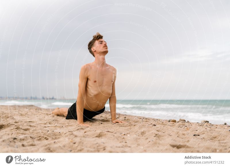 Yogi-Mann in Kobra-Pose am Strand Yoga üben bhujangasana Sand Asana verdrehen männlich schlank ohne Hemd MEER Gesundheit Lifestyle Gleichgewicht nackter Torso