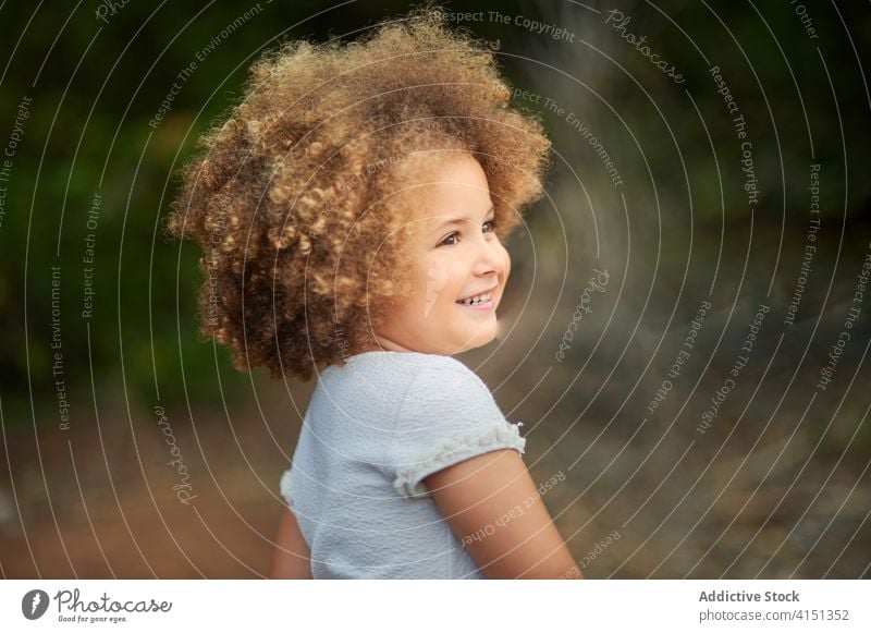 Glückliches Mädchen mit lockigem Haar im Sommerfeld krause Haare Feld heiter Kind Lächeln Porträt gemischte Rasse bezaubernd Frisur niedlich Freude Frau