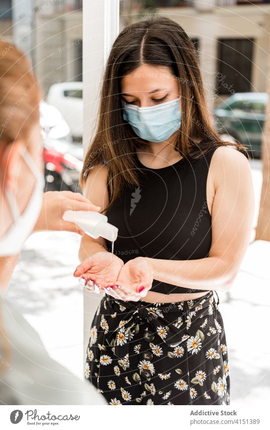 Frau mit medizinischer Maske beim Desinfizieren der Hände vor dem Betreten des Salons Coronavirus desinfizieren Hand Desinfektionsmittel behüten Eingang Klient