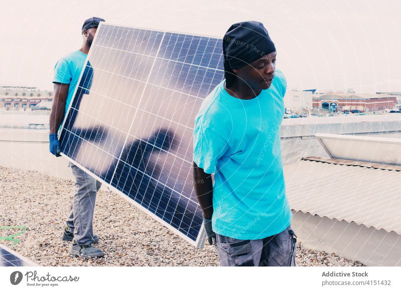 Ethnische Männer mit Sonnenkollektoren auf einer Baustelle solar Panel industriell alternativ Arbeit Konstruktion Standort nachhaltig Erneuerung ethnisch