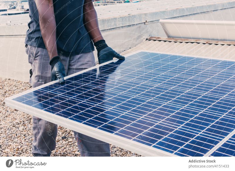 Ethnischer Mann mit Solarpanel auf einer Baustelle solar Panel industriell alternativ Arbeit Konstruktion Standort nachhaltig Erneuerung ethnisch schwarz