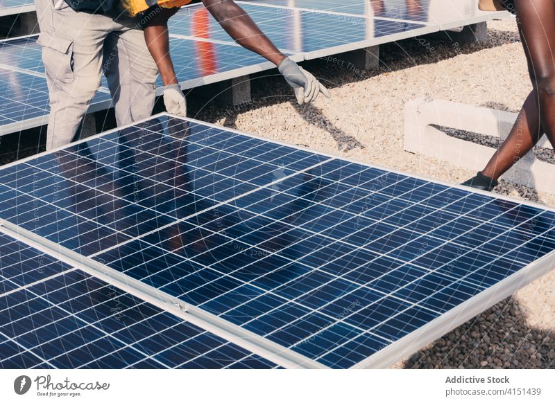 Anonyme ethnische männliche Arbeiter mit Sonnenkollektoren im Industriegebiet solar Panel installieren Batterie Männer Ingenieur Zusammensein alternativ