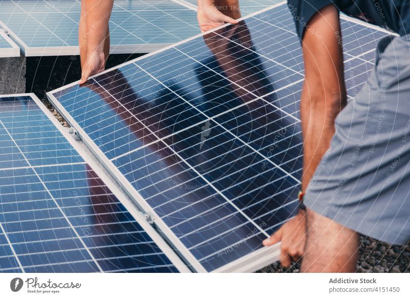 Anonyme männliche Arbeiter mit Sonnenkollektoren im Industriegebiet solar Panel installieren Batterie Männer Ingenieur Zusammensein alternativ nachhaltig