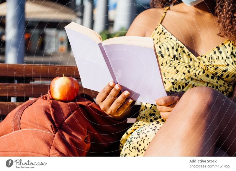 Schwarze Frau liest Buch auf der Straße lesen nachdenklich Leseratte Windstille genießen Großstadt Wochenende ethnisch schwarz Afroamerikaner Mundschutz