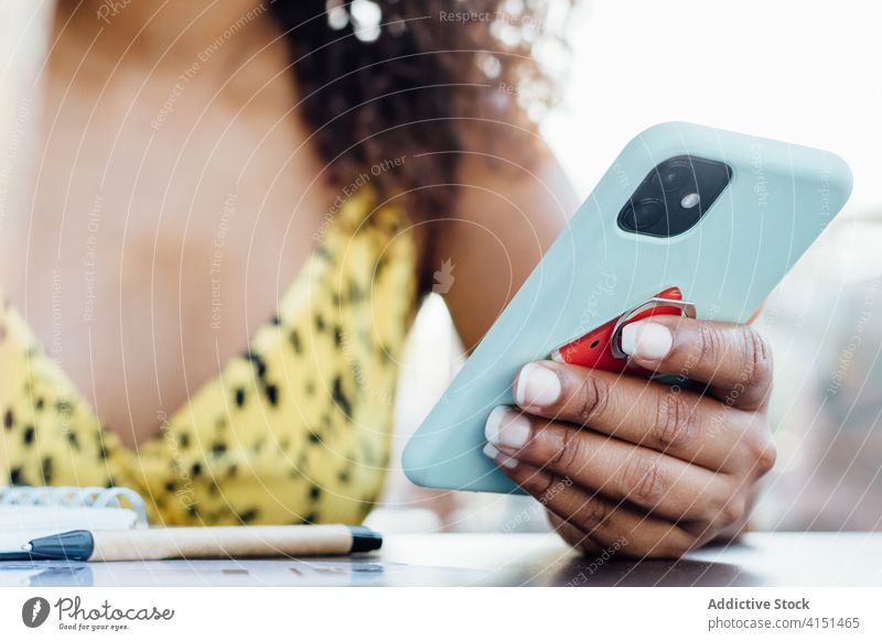 Crop ethnische Frau surft auf dem Handy Smartphone Browsen Café soziale Netzwerke Talkrunde sich[Akk] entspannen unterhalten benutzend Kantine schwarz