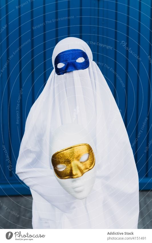 Anonymes Kind im Geisterkostüm auf der Straße Tracht Halloween Mundschutz Maskerade Feiertag Veranstaltung Herbst Großstadt Gebäude urban Anzug beängstigend