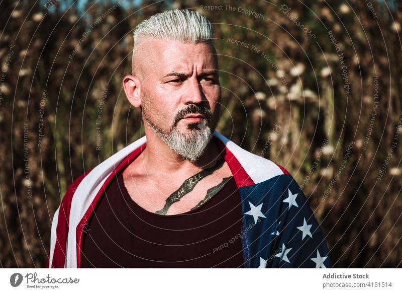 Brutaler erwachsener Mann mit amerikanischer Flagge brutal ernst Vollbart Fahne Amerikaner selbstbewusst hart Porträt stark Erwachsener männlich Tattoo