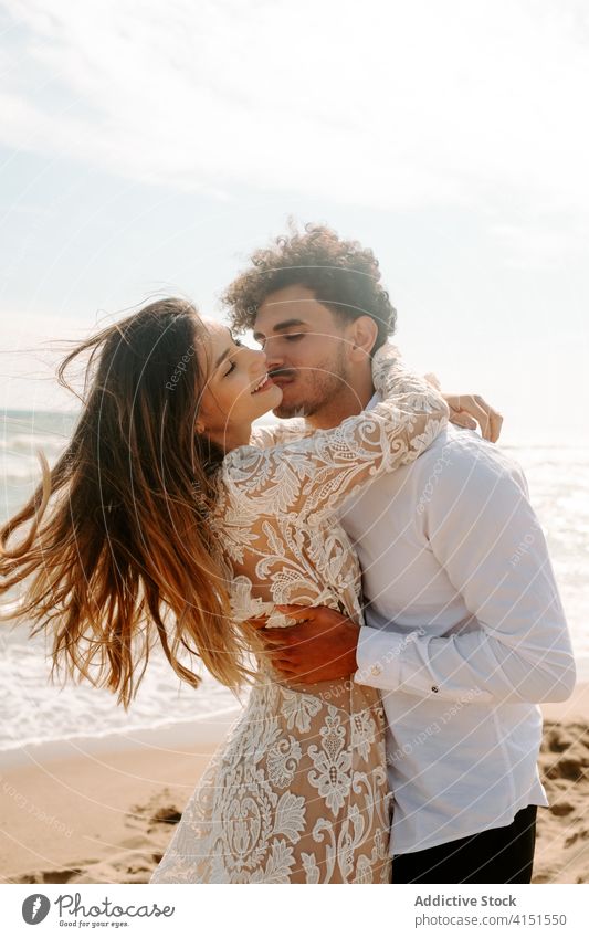 Glückliches frisch verheiratetes Paar steht gegen wogende Meer Jungvermählter Strand romantisch heiter Zusammensein Umarmen Partnerschaft MEER Liebe Natur Sand