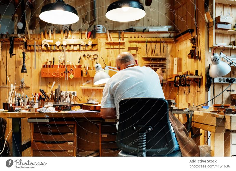 Handwerker bei der Arbeit in einer modernen Werkstatt mit Werkzeugen Kunsthandwerker Kunstgewerbler Zupfinstrumentenmacher Mann Reparatur machen
