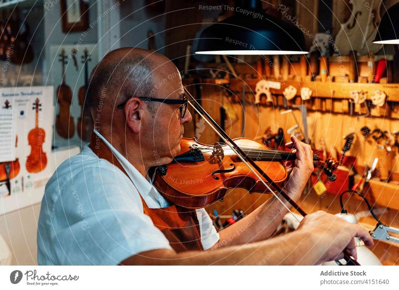Geigenbaumeister spielt Geige in der Werkstatt Zupfinstrumentenmacher spielen Prüfung Instrument Schleife Musik prüfen Mann Kunstgewerbler Reparatur