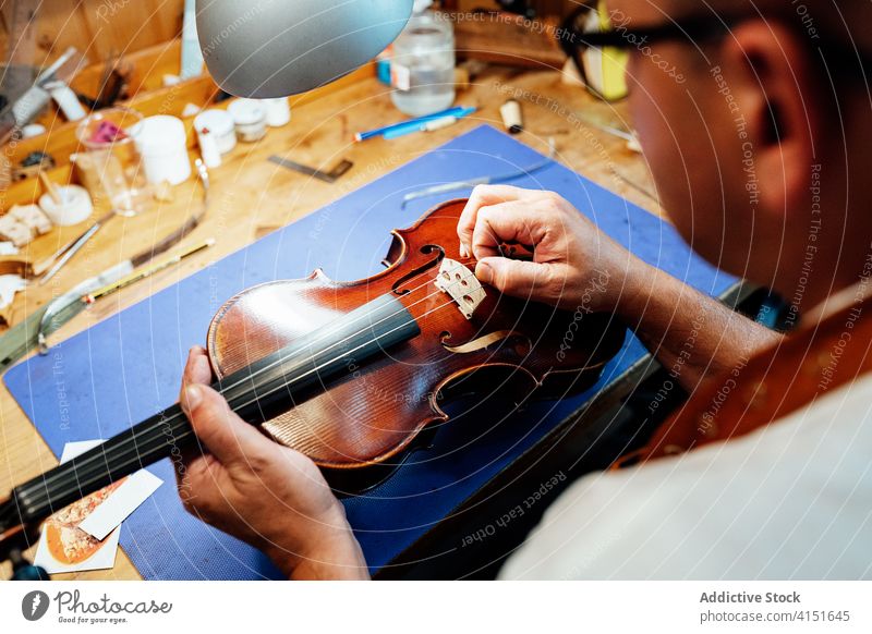 Handwerker beim Zusammenbau des Stegs einer Geige Reparatur Brücke Schnur Zupfinstrumentenmacher Kunsthandwerker Kunstgewerbler wiederherstellen Arbeit