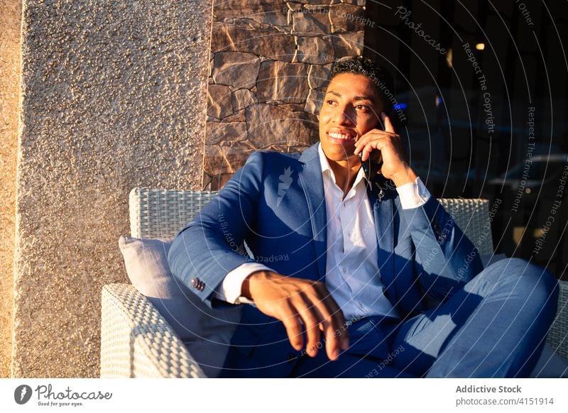 Eleganter junger Geschäftsmann, der mit seinem Smartphone spricht reden elegant Erfolg Glück Kommunizieren positiv formal Stuhl Mann Afroamerikaner schwarz