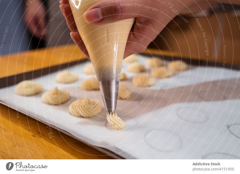 Gesichtsloser Koch, der Teig auf ein Backblech spritzt Bäcker Gebäck Backwarenbeutel Röhren Prozess drücken Bäckerei professionell Kleinunternehmen heimwärts