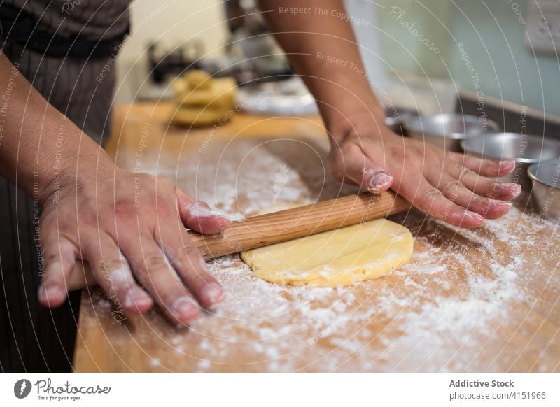 Anonyme Person beim Ausrollen von Teig beim Backen zu Hause Bäcker heimwärts Teigwaren Nudelholz Team Mürbeteig Küche erklären Koch manifestieren vorbereiten