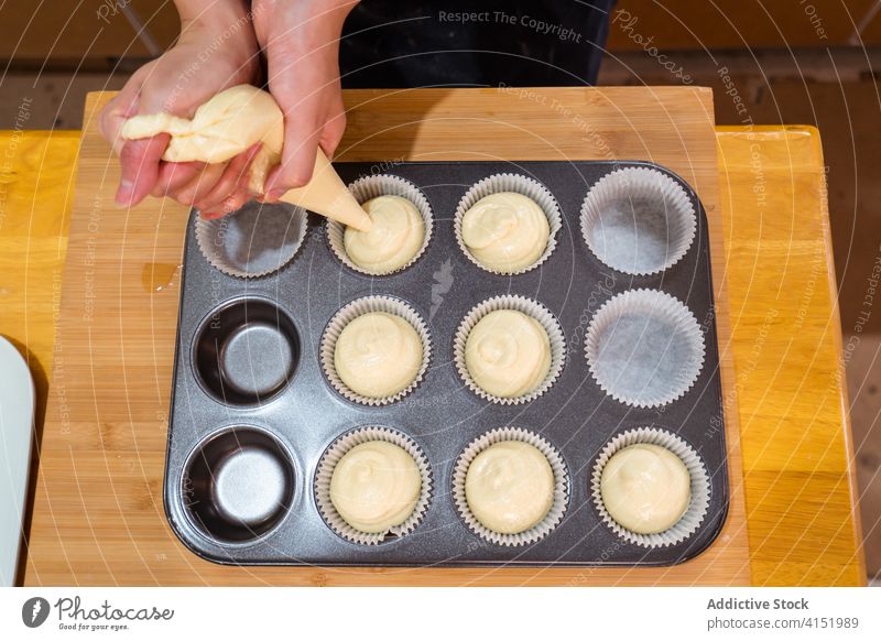 Gesichtsloser Bäcker füllt Backformen Muffin Teig Formular eingießen Cupcake Backwarenbeutel Spritzbeutel Teigwaren besetzen lecker Bäckerei Küche Feinschmecker